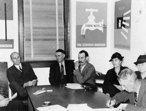 A group of individuals sitting around a table with posters on the wall.