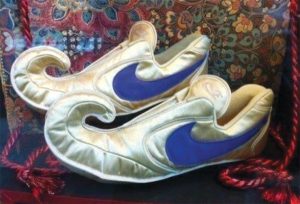 An image of silver shoes with curled feet with a blue Nike swoosh on the sides.