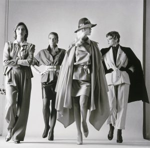 A black and white image of 4 women dramatically posing draped with clothes on.