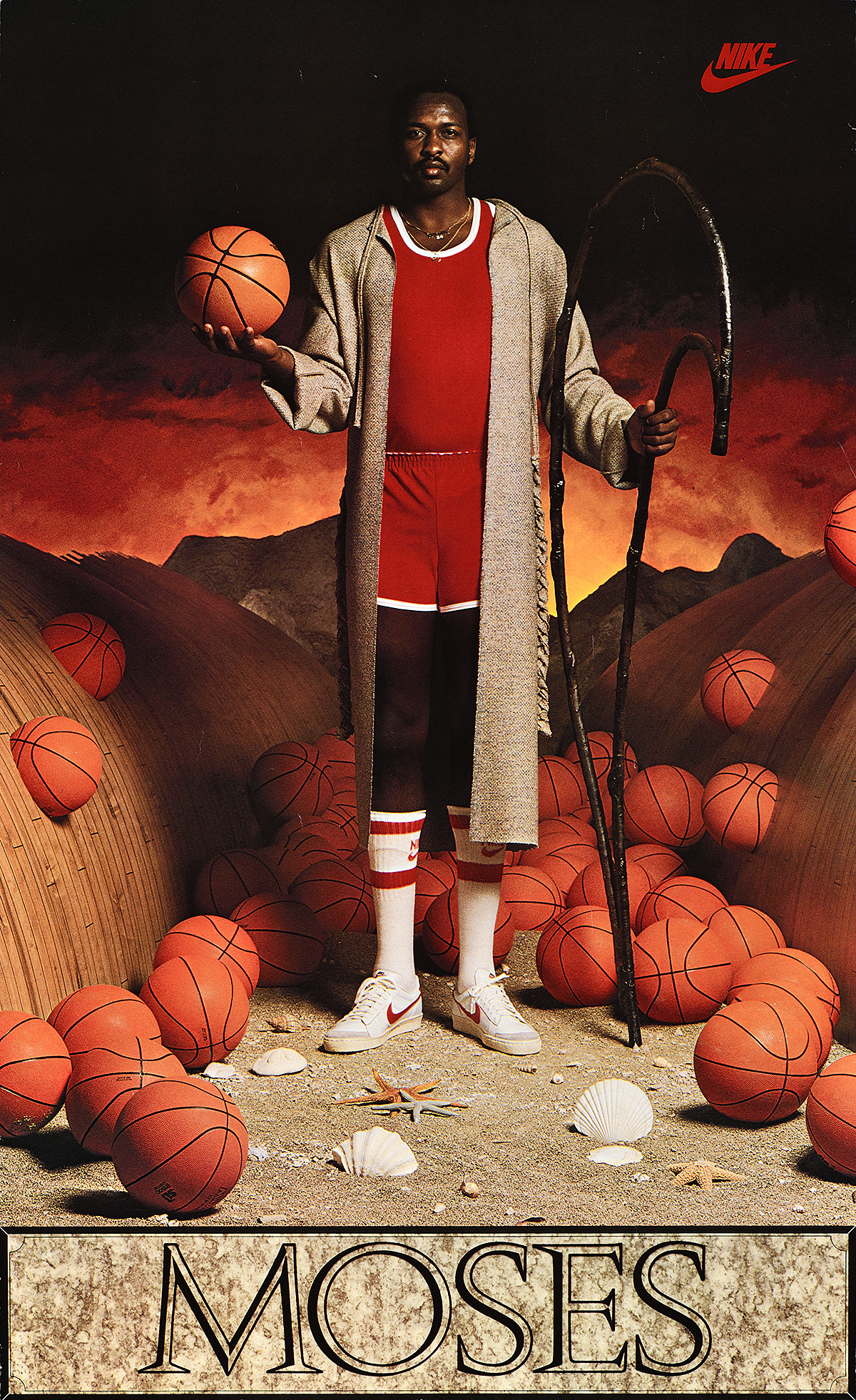 A Black man holding a staff shaped like a Nike swoosh in a parted sea of basketballs.