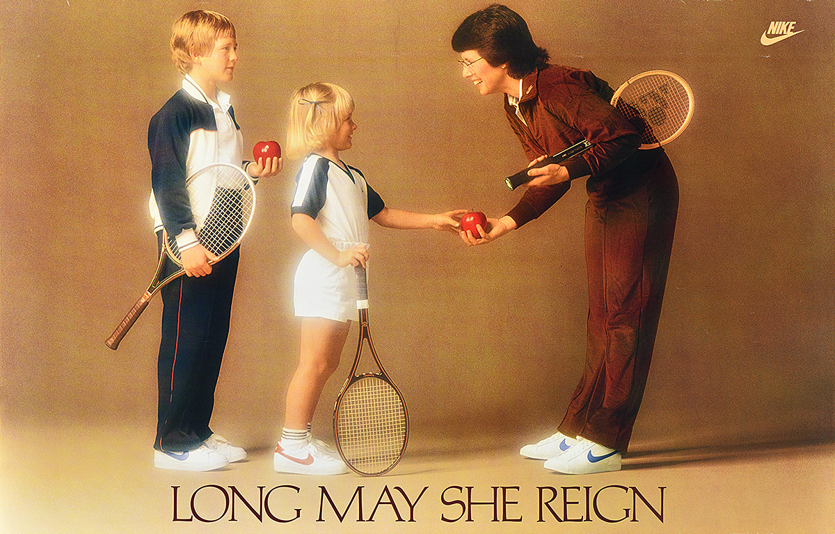 A white woman with a tennis racquet under her arm, bending to accept an apple from 2 children.