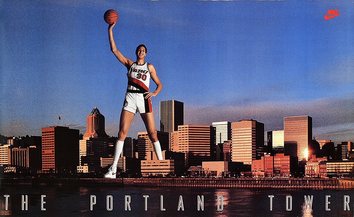 A poster of a male basketball player holding a ball in his hand above the Portland city skyline.