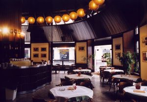 A photo of a restaurant with circular lanterns and slats on the ceilings.