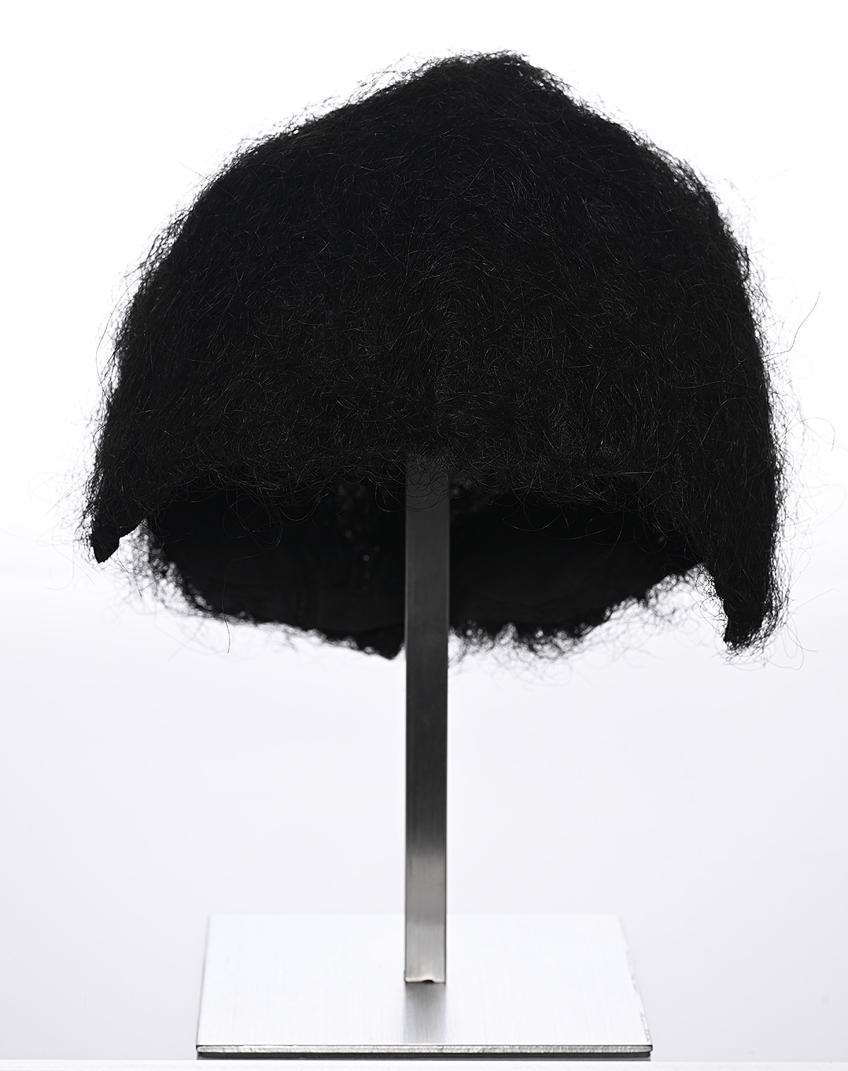 A black wig on a thin metal stand.